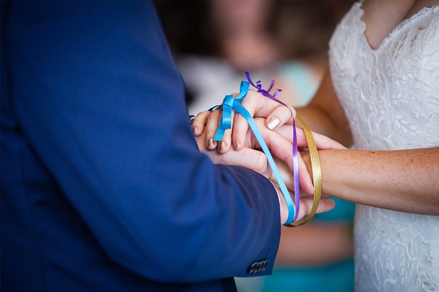 Bride and groom's hands united during handfasting wedding ceremony