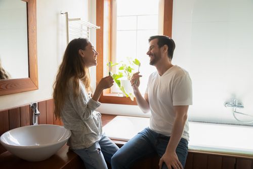 Couple Laughing as They Brush Their Teeth