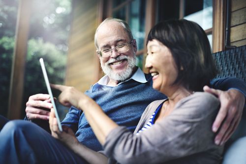 Couple Laughing Together While Looking at a Tablet