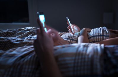 A Couple Looking at Their Phones in Bed