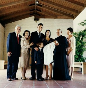 Portrait of a Three Generational Family Standing in a Church With a Priest and a Baby in a Christening Gown