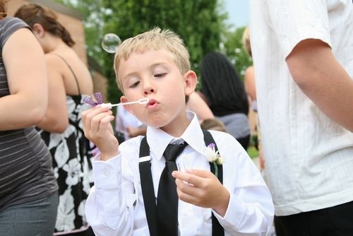 a young boy blowing bubbles at a wedding