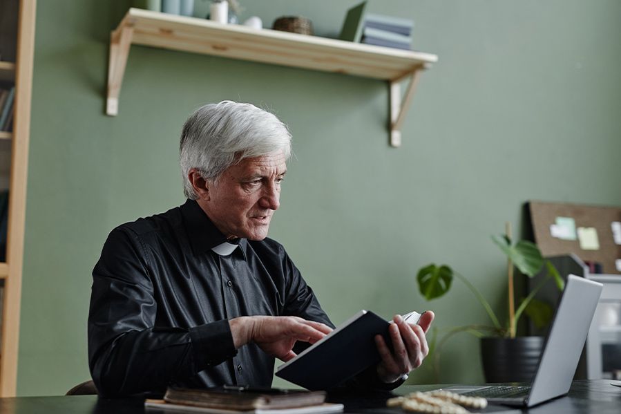 male minister in clergy collar holding a book