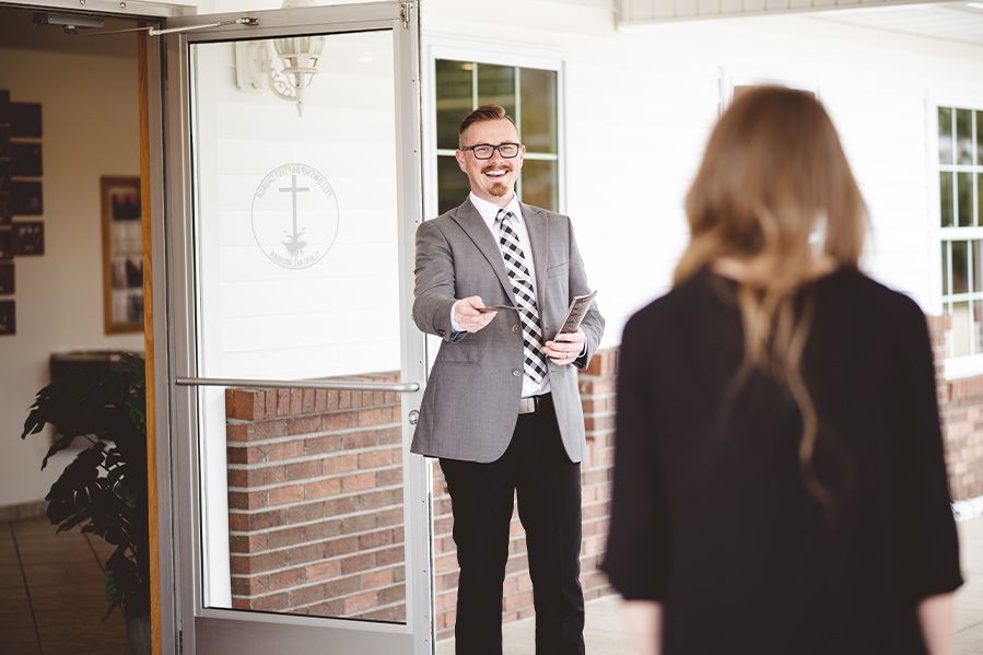 greeter outside church entrance handing out pamphlets