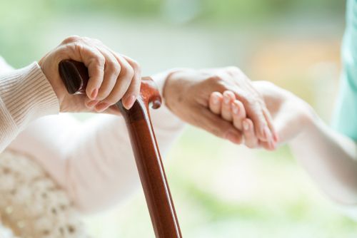 Person With a Cane Holding Hands With a Caregiver