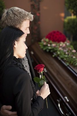 Two people mourning over casket
