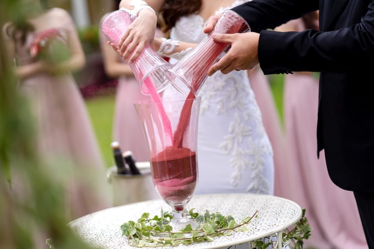 Offbeat bride and groom pouring pink sand together